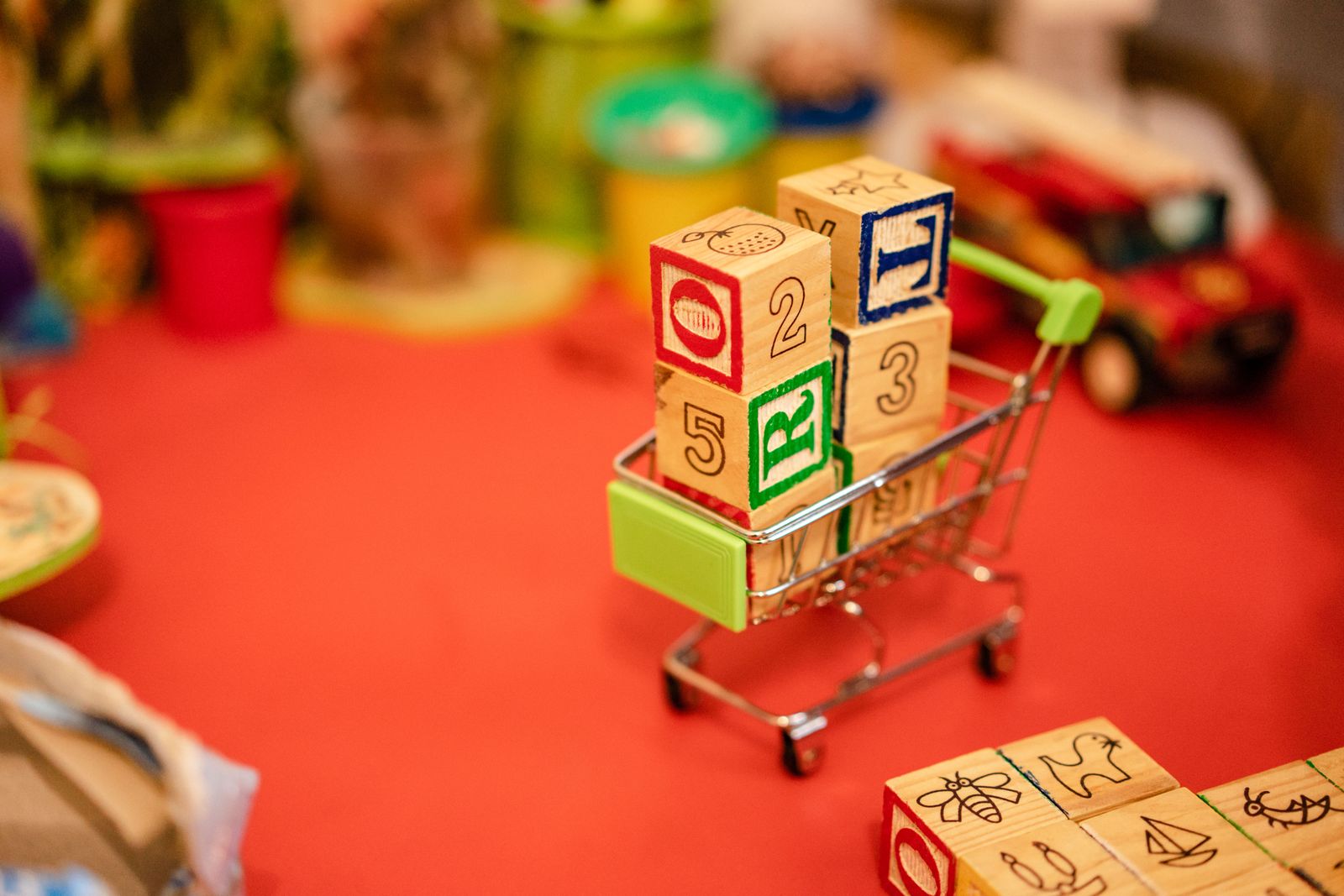 Miniature shopping cart filled with vibrant wooden blocks on a playful background.