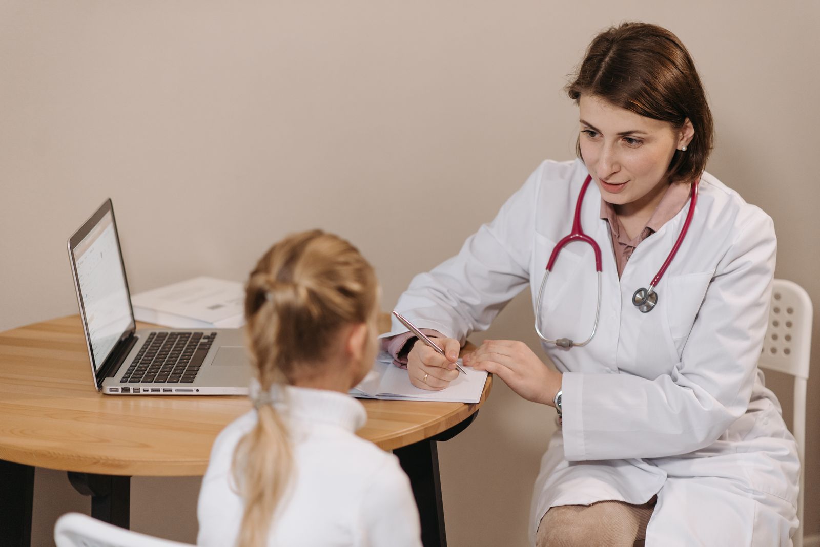 A clinician talking with a parent and child in a consultation room