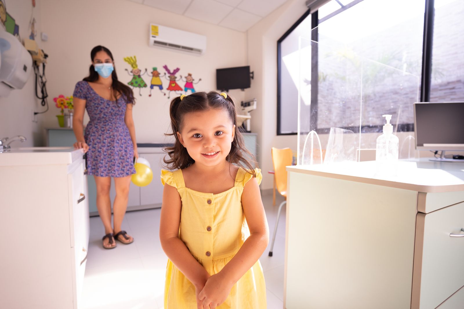 A young child standing against a height chart while a clinician measures them